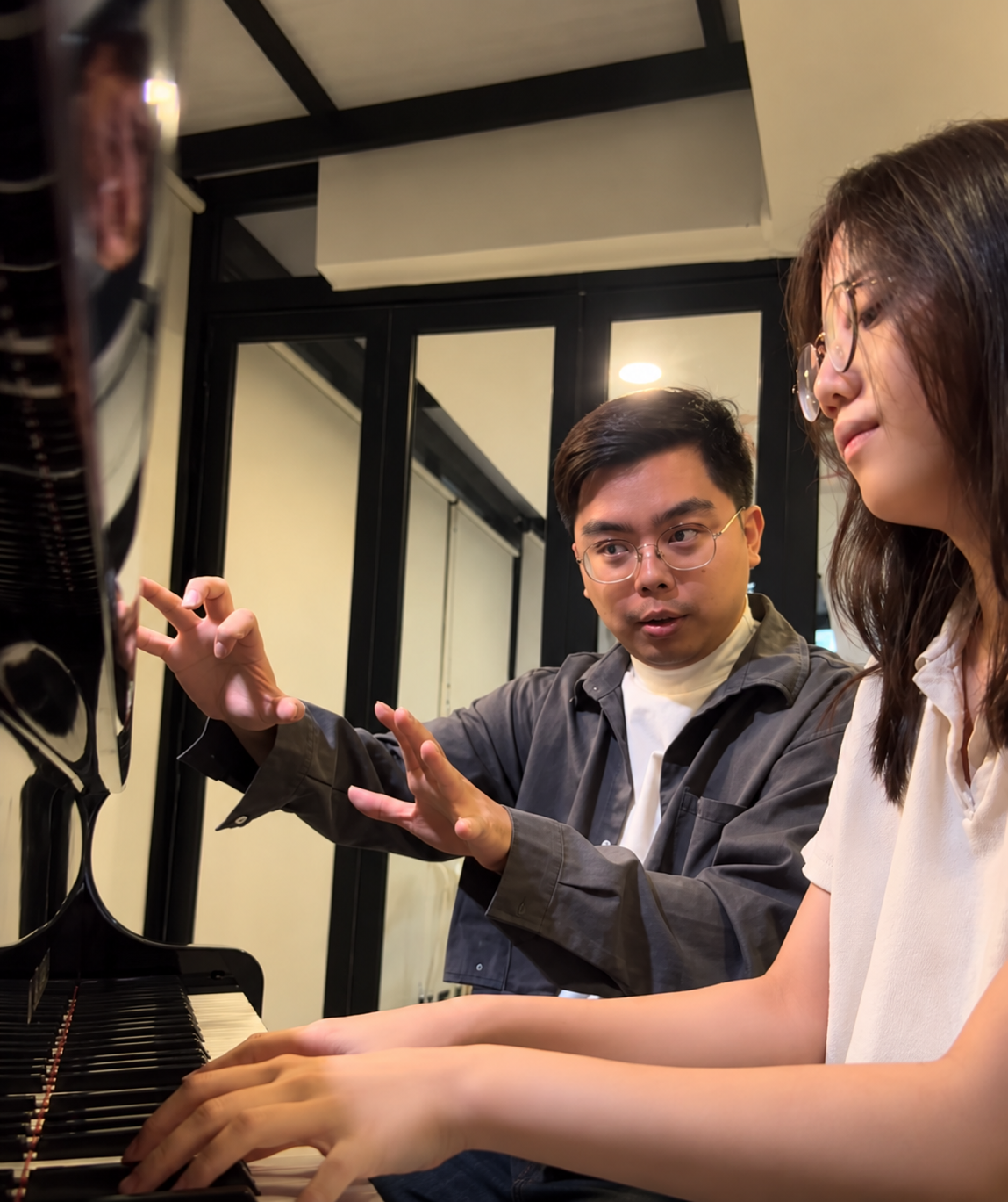 A piano teacher guiding a learner during a lesson